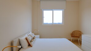 Une chambre à coucher avec un lit, une table de chevet, une chaise et une fenêtre.