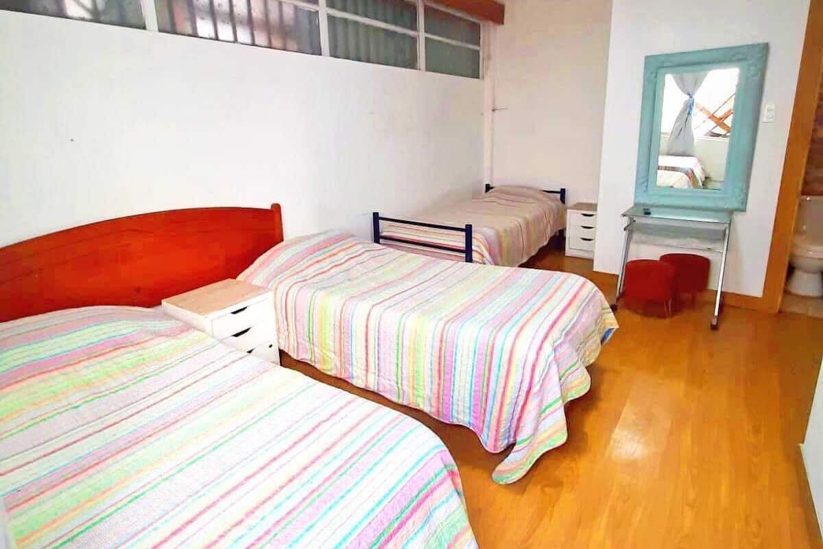 Une chambre de dortoir avec deux lits simples, un petit bureau et un miroir au mur.
