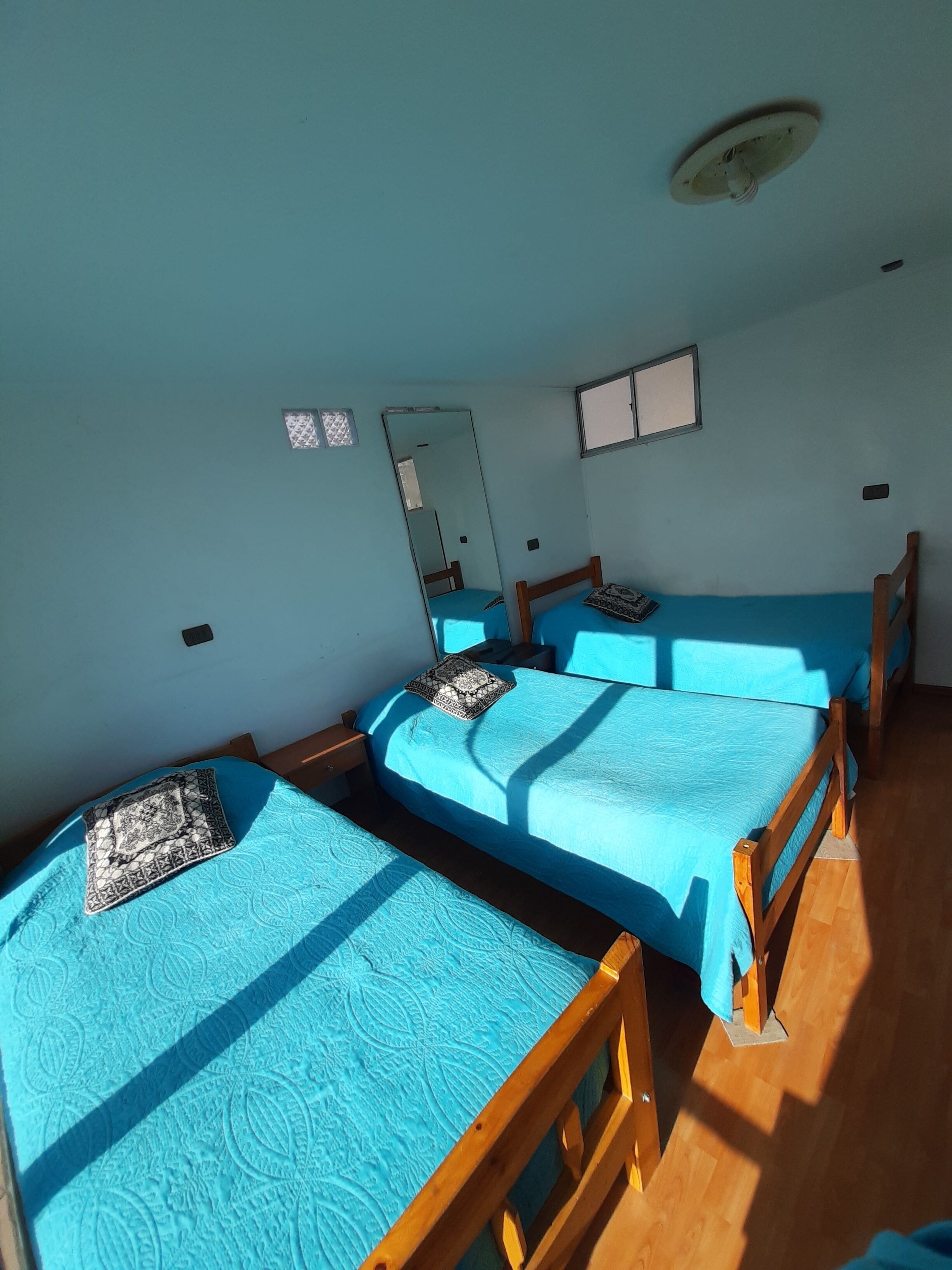 Ein Zimmer mit drei Einzelbetten, jedes mit einer gemusterten Bettdecke und einem Kissen.