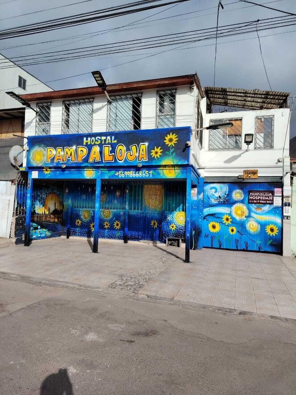 Un edificio con fachada azul y un letrero que dice 'HOSTAL PAMPALONA'.