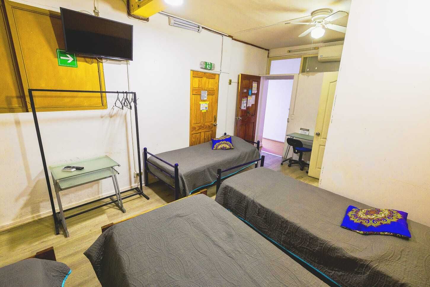 Un dormitorio con dos camas individuales, un escritorio, una silla, un televisor y una mesita.