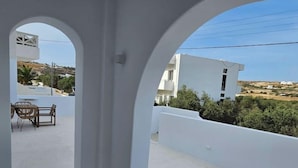 A balcony with a table and chairs, white walls, and a view of the landscape. - Aristotle Suites, Aegle
 (Adamantas)