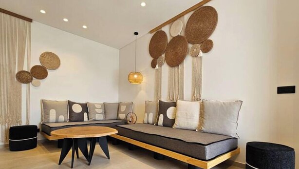 A modern living room with a sectional sofa, a wooden coffee table, and decorative wall art. - Aristotle Suites, Aegle
 (Adamantas)