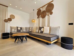A modern living room with a sectional sofa, a wooden coffee table, and decorative wall art. - Aristotle Suites, Aegle
 (Adamantas)