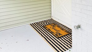 A house entrance with a white door, a doormat, and a wreath on the wall. - Charming 3-bedroom house in peaceful neighborhood  (Bloomington)