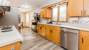 A modern kitchen with wooden cabinets, stainless steel appliances, and a large window. - Charming 3-bedroom house in peaceful neighborhood  (Bloomington)