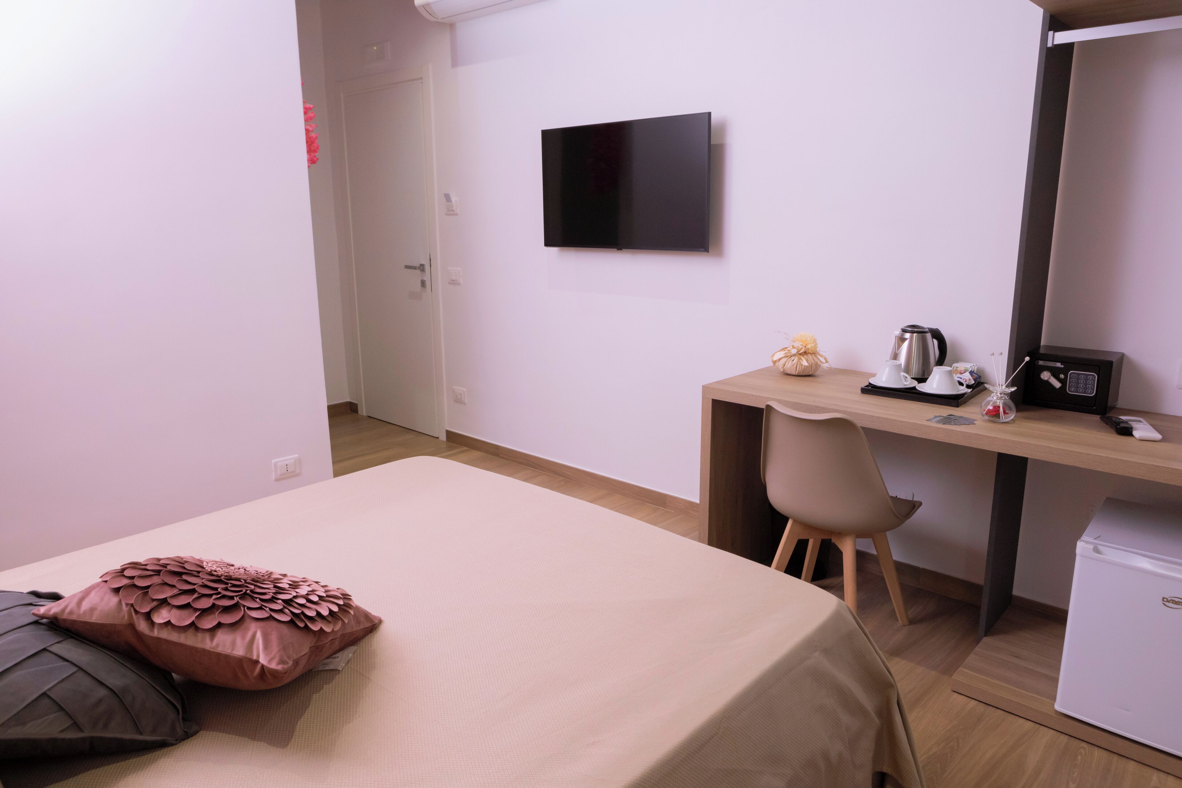 A hotel room with a bed, a desk, a chair, a TV, a coffee maker, and a refrigerator.