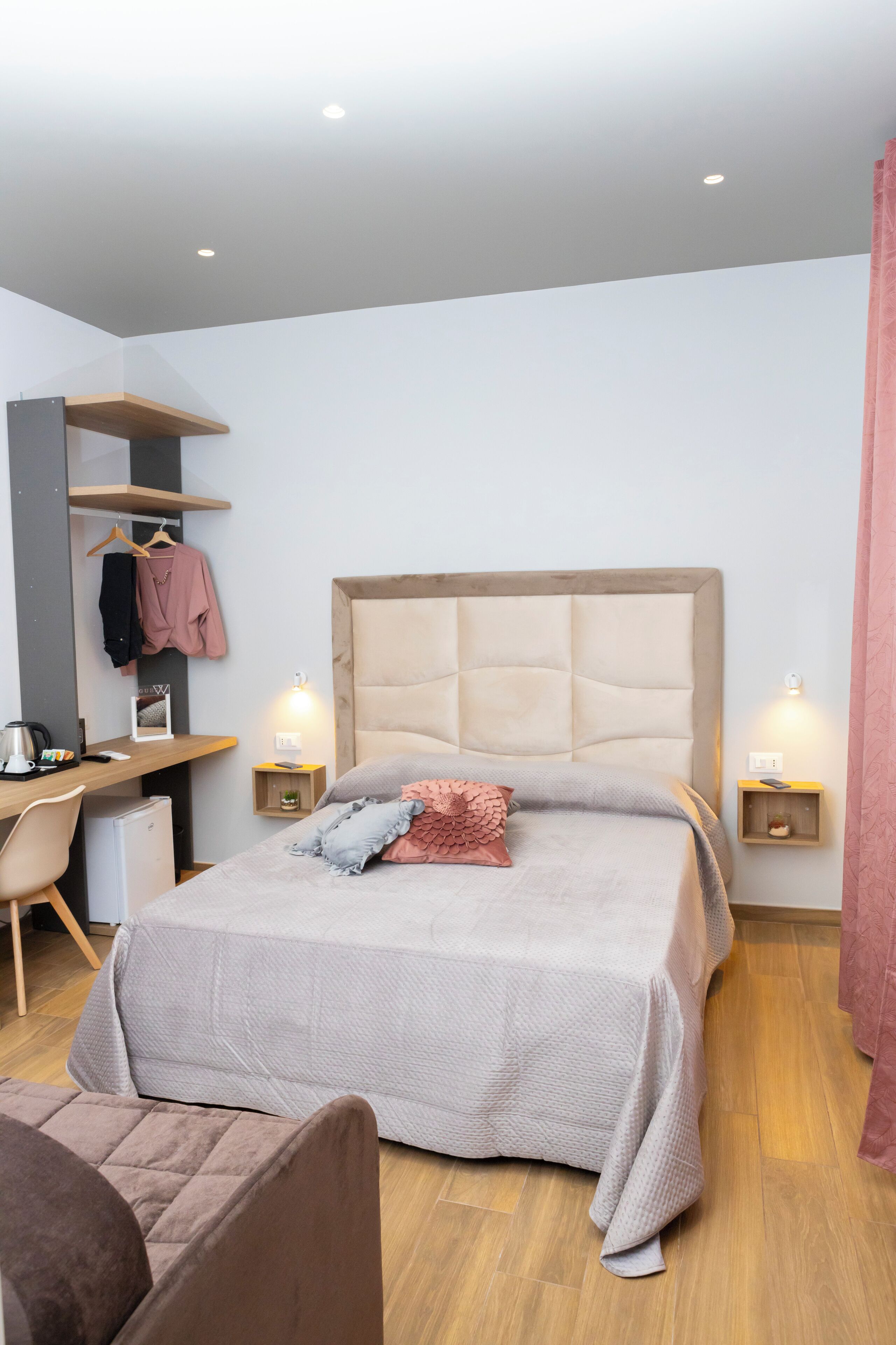 A bedroom with a bed, bedside tables, a desk, and a chair.