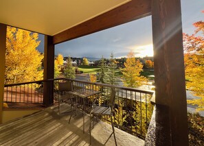 Un balcon avec vue sur un terrain de golf et sur des arbres aux couleurs automnales.