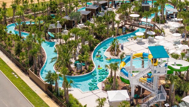 An aerial view of a resort with a large swimming pool, water slides, and palm trees. - 1268- Great 5 Bedroom Home, Pool & Game Room (Clermont)