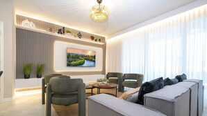 A modern living room with a sofa set, armchairs, a coffee table, and a TV mounted on the wall. - 1268- Great 5 Bedroom Home, Pool & Game Room (Clermont)