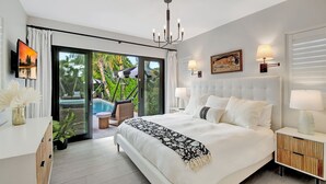 A modern bedroom with a large bed, a TV, a chandelier, and a sliding glass door leading to a balcony with a pool.