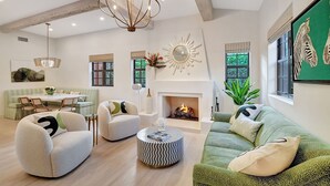A spacious living room with a fireplace, modern furniture, and a chandelier.