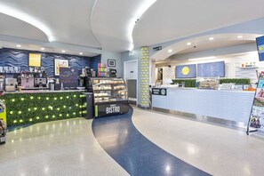 Ein modernes Bistro mit einer gebogenen Theke, einer Kaffeemaschine und einer Speisekarte.