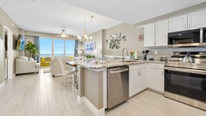 A modern kitchen with white cabinets, stainless steel appliances, and a large island.