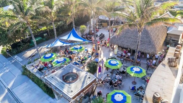 An outdoor patio area with thatched-roof structures, umbrellas, and seating arrangements. - Casa Calma
2 min to Famous Atlantic Ave, Pool coming Oct 2025 (Delray Beach)
