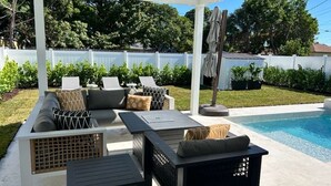 An outdoor patio with a pool, covered seating area, and a ceiling fan. - Casa Calma
2 min to Famous Atlantic Ave, Pool coming Oct 2025 (Delray Beach)