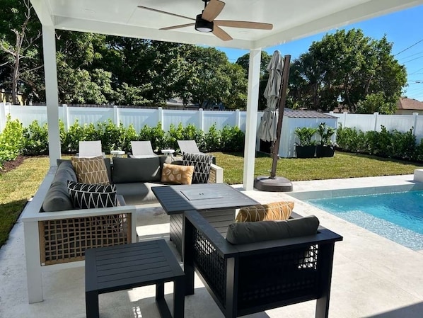 Eine Außenpatio mit Pool, überdachter Sitzgruppe und Deckenventilator.