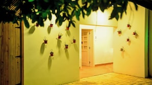 A hallway with a wooden door, a tiled floor, and multiple small potted plants on the walls. - Honky Tonk Colonial (Santo Domingo)
