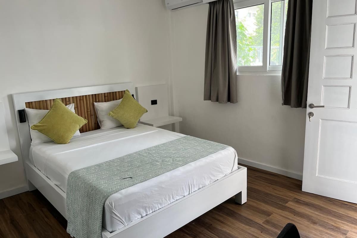 A neatly arranged bedroom with a bed, bedside tables, and a window with curtains.