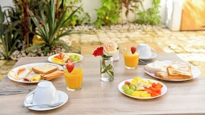 A breakfast table with plates of toast, eggs, and fruit, along with glasses of orange juice. - Honky Tonk Colonial (Santo Domingo)