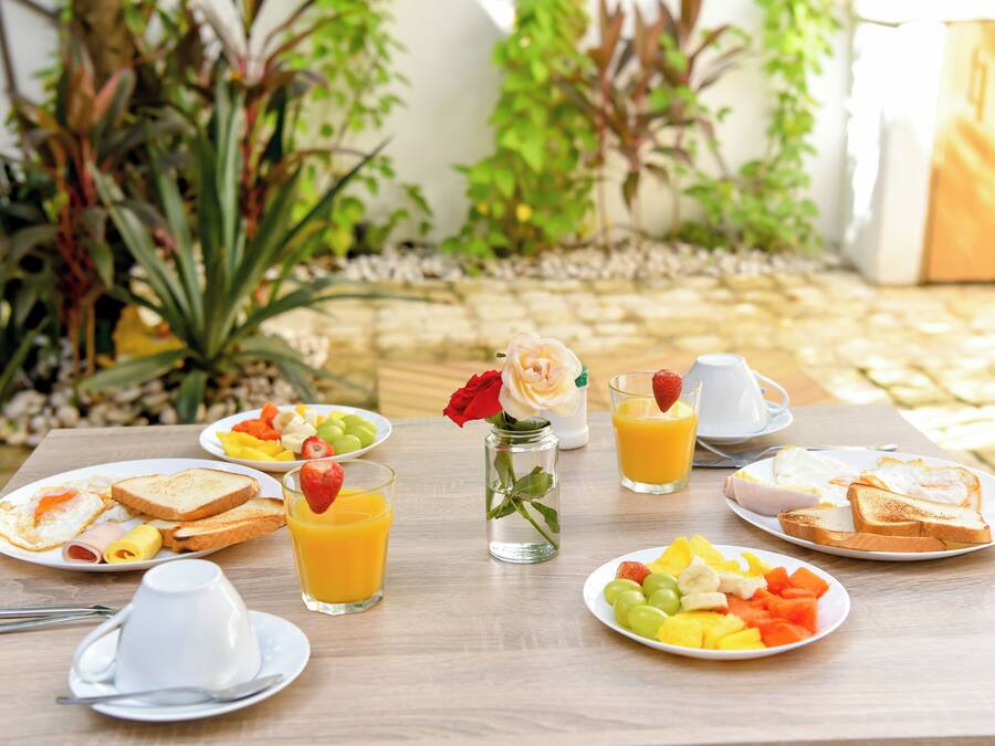 Een ontbijttafel met toast, eieren en fruit, plus glazen jus d'orange.