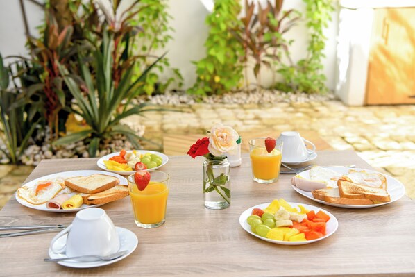 A breakfast table with plates of toast, eggs, and fruit, along with glasses of orange juice. - Honky Tonk Colonial (Santo Domingo)
