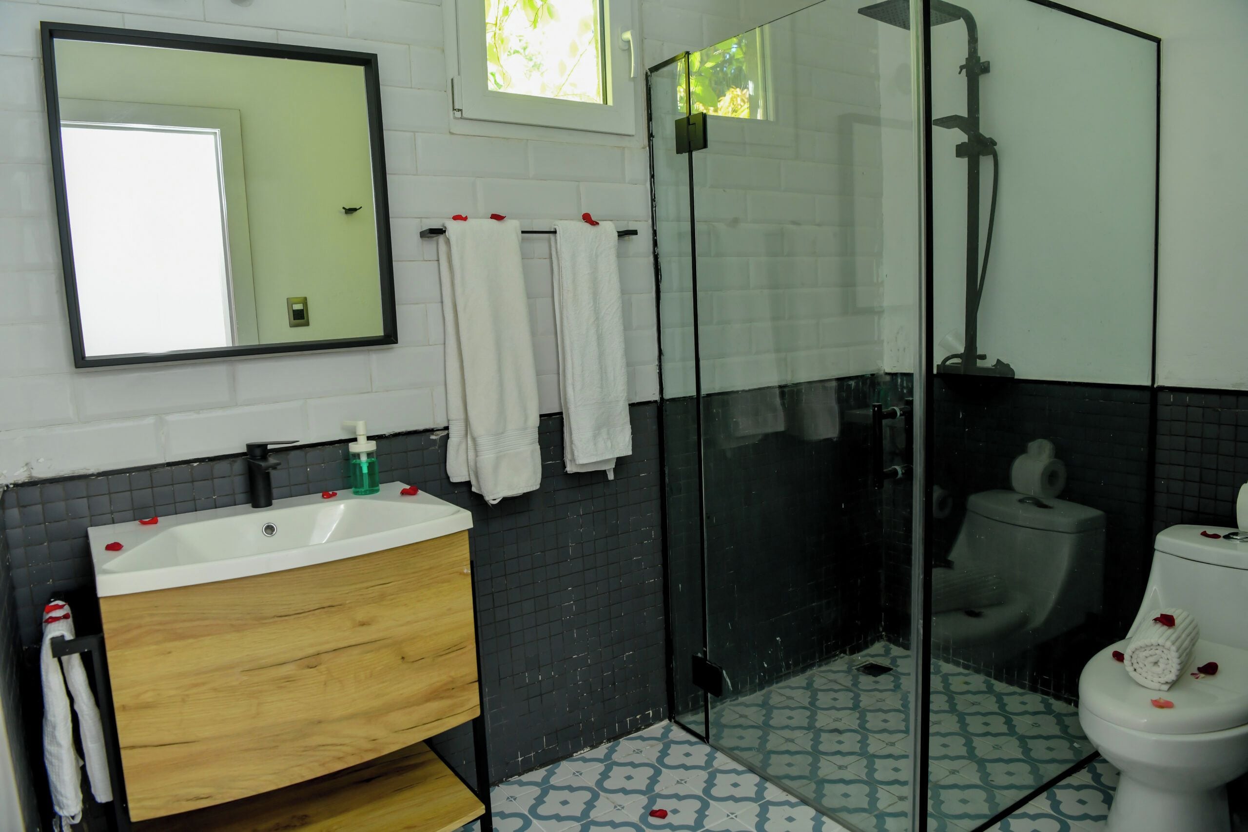 Un bany amb un rentamig, un mirall, una cabina de dutxa de vidre i un vàter.