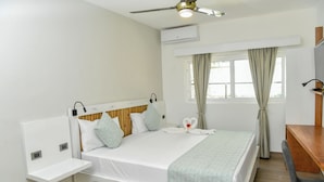 A neatly arranged bedroom with a bed, bedside tables, a desk, and a ceiling fan. - Honky Tonk Colonial (Santo Domingo)