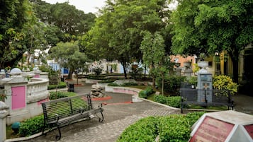 Un parque con un sendero pavimentado, bancos y varios árboles.