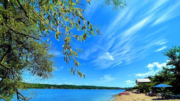 A beach with boats, a clear sky, and a calm lake.