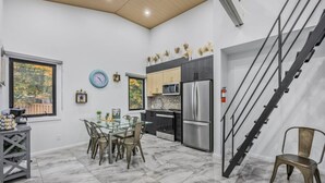 A modern kitchen with a dining area, a staircase, and a view of the outdoors.