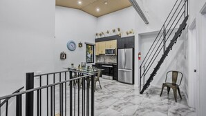 A modern kitchen with a dining area, a staircase, and a view of the city.