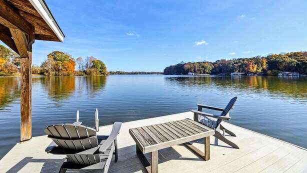A wooden dock with chairs and a table overlooking a calm lake with autumn trees in the background. - Lakefront Lake Anna - Views, Boat Dock, Games (Mineral)