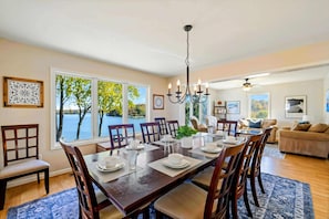 A dining room with a large table set for six, surrounded by chairs, with a view of the outdoors through large windows. - Lakefront Lake Anna - Views, Boat Dock, Games (Mineral)