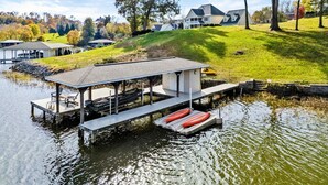A lakeside dock with a covered seating area, a boat, and a small building. - Lakefront Lake Anna - Views, Boat Dock, Games (Mineral)