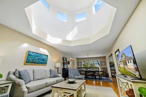 A living room with a sofa, coffee table, and a television. There is a dining area with chairs and a table. - Lakefront Lake Anna - Views, Boat Dock, Games (Mineral)