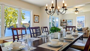 A dining room with a long table set for four, large windows, a chandelier, and a ceiling fan. - Lakefront Lake Anna - Views, Boat Dock, Games (Mineral)