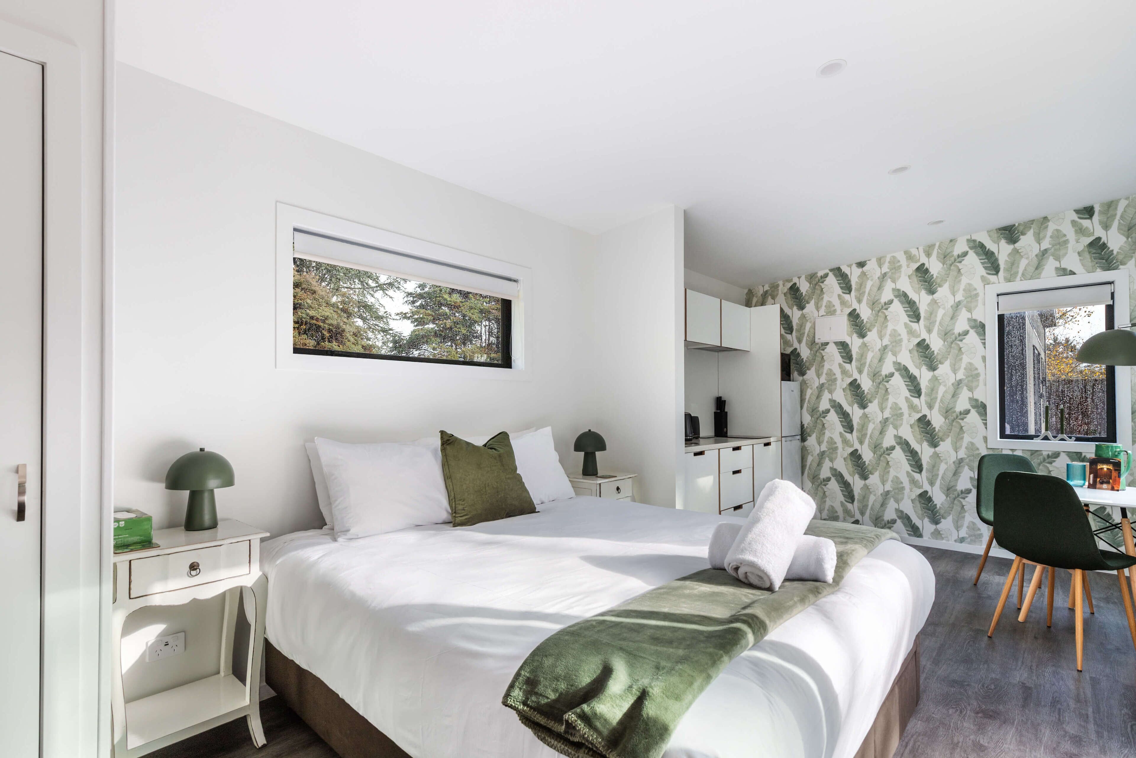 Een moderne hotelkamer met een groot bed, een bureau en een stoel.