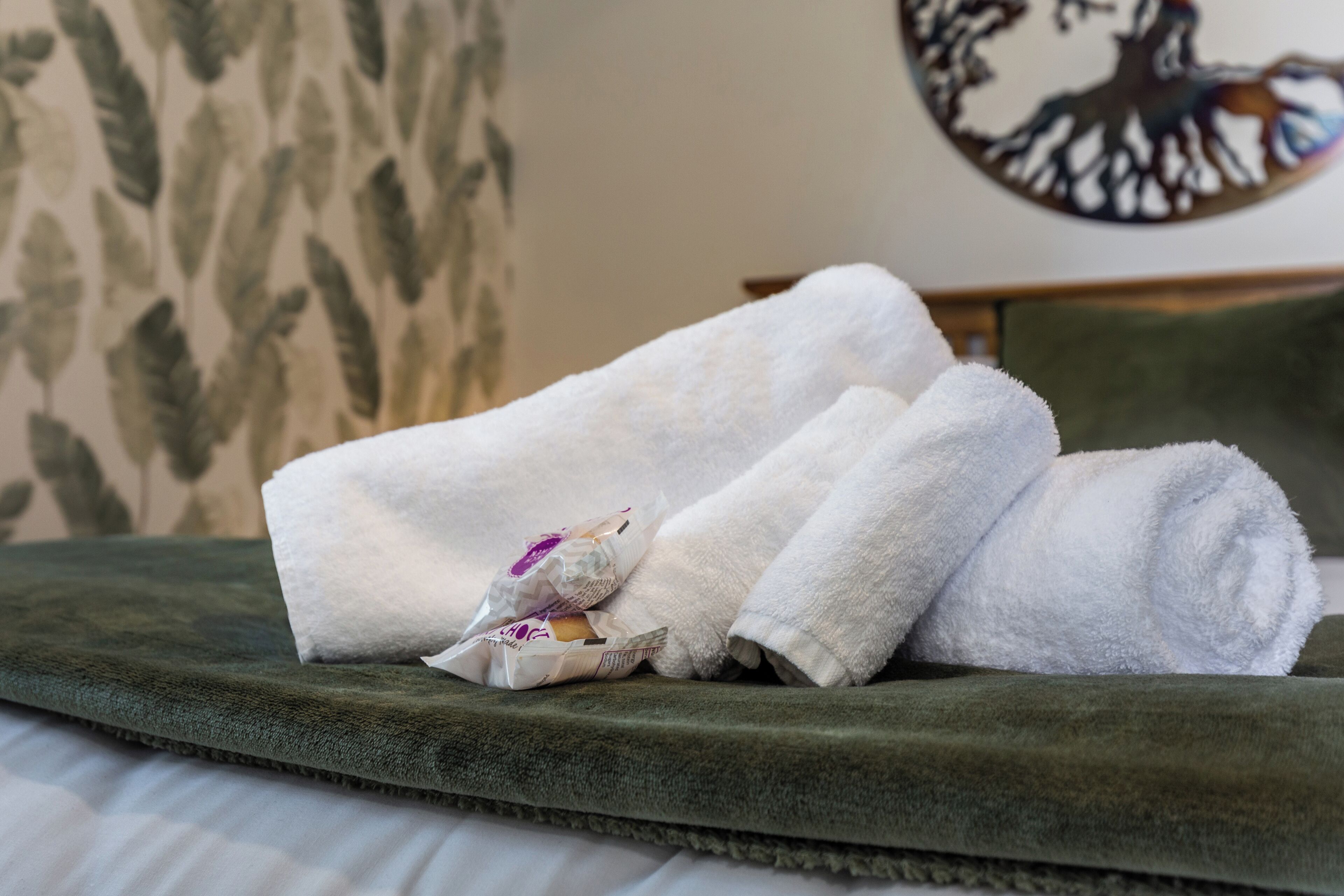 A neatly made bed with green bedding and white towels.