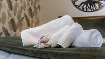 A neatly made bed with green bedding and white towels.