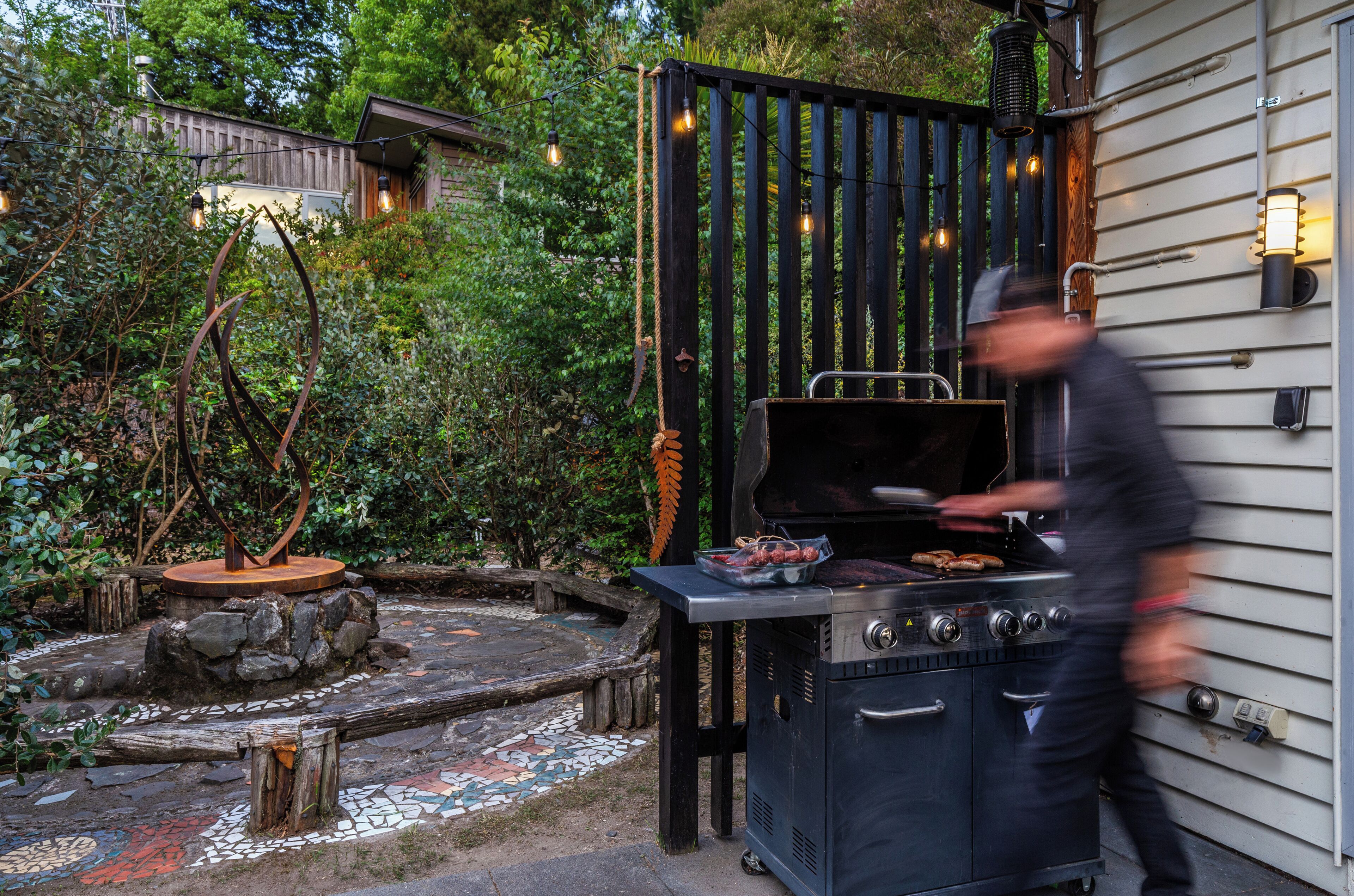 En trädgård med en grill, ett trästaket och en gång av sten.