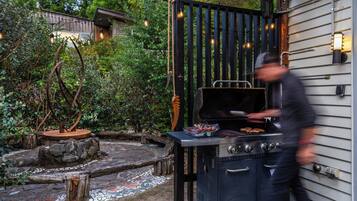 Un jardin avec un barbecue, une clôture en bois et un chemin pavé de pierres.