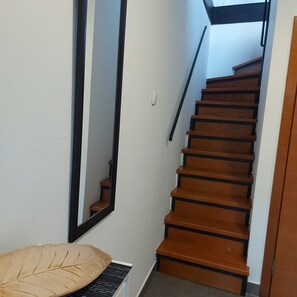 A staircase with wooden steps and black handrails, leading to an upper floor.