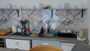 A modern kitchen with a marble backsplash, a sink, and a wooden bowl on the counter. - Hidden place in pedestrian zone (Novi Sad)