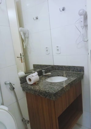 Ein Badezimmer mit Waschbecken, Toilette und einem an der Wand montierten Föhn.