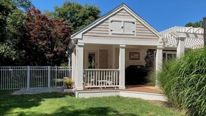 A single-story house with a front porch, a garage, and a fenced yard. - New Eastham Oceanside Guest Suite with Pool and Hot Tub (Eastham)