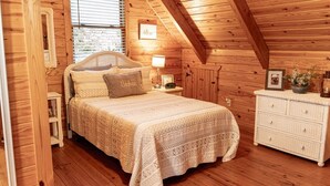 A cozy bedroom with a wooden ceiling, a bed with a patterned bedspread, a nightstand with a lamp, and a dresser with decorative items. - Visit Star Haven for Labor Day - Fiber Wifi! - Close to Callway Gardens (Warm Springs)