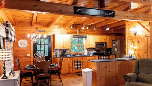 A wooden cabin interior with a dining area, kitchen, and a cozy living space. - Visit Star Haven for Labor Day - Fiber Wifi! - Close to Callway Gardens (Warm Springs)