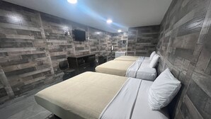 Ett modernt hotellrum med två sängar, ett skrivbord och en tv som är monterad på väggen.